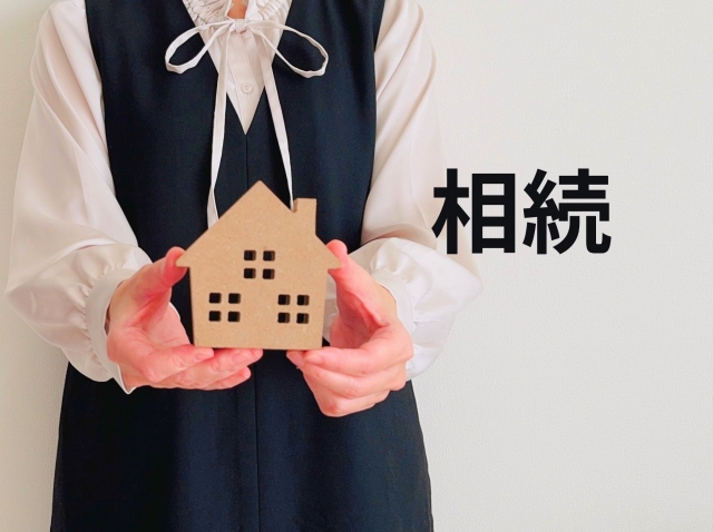 家の模型を手に持つ女性と「相続」の文字