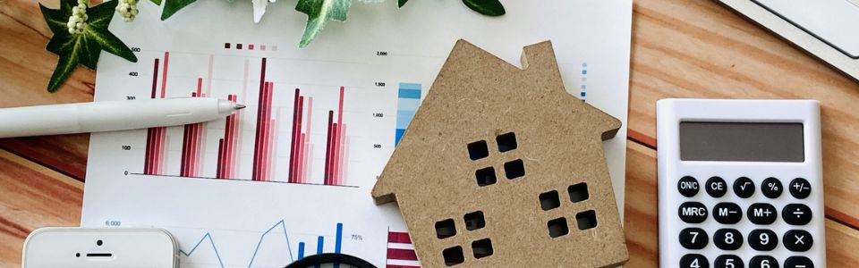 家の模型と電卓・統計グラフ資料を使った不動産価格分析のイメージ