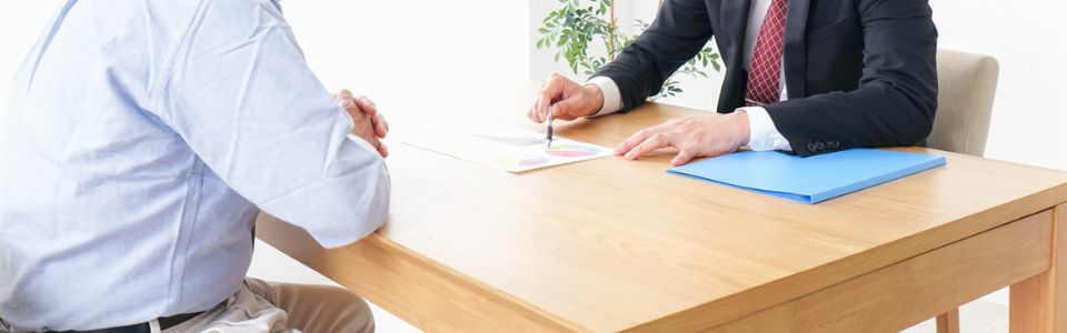 不動産会社の担当者が書類を使って顧客に説明している商談風景