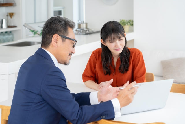 不動産営業担当者がノートパソコンを使いながら女性顧客に物件を提案する様子