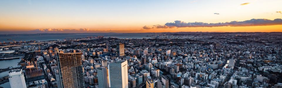 夕焼け空に染まる横浜市街地の高層ビル群を上空から望むパノラマ