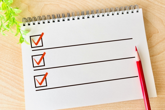 赤いチェックマークが3つ並んだチェックリストと赤鉛筆による確認項目のイメージ